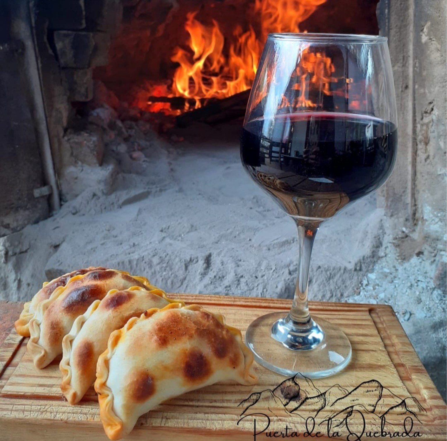 Empanadas y una copa de vino junto al horno de barro